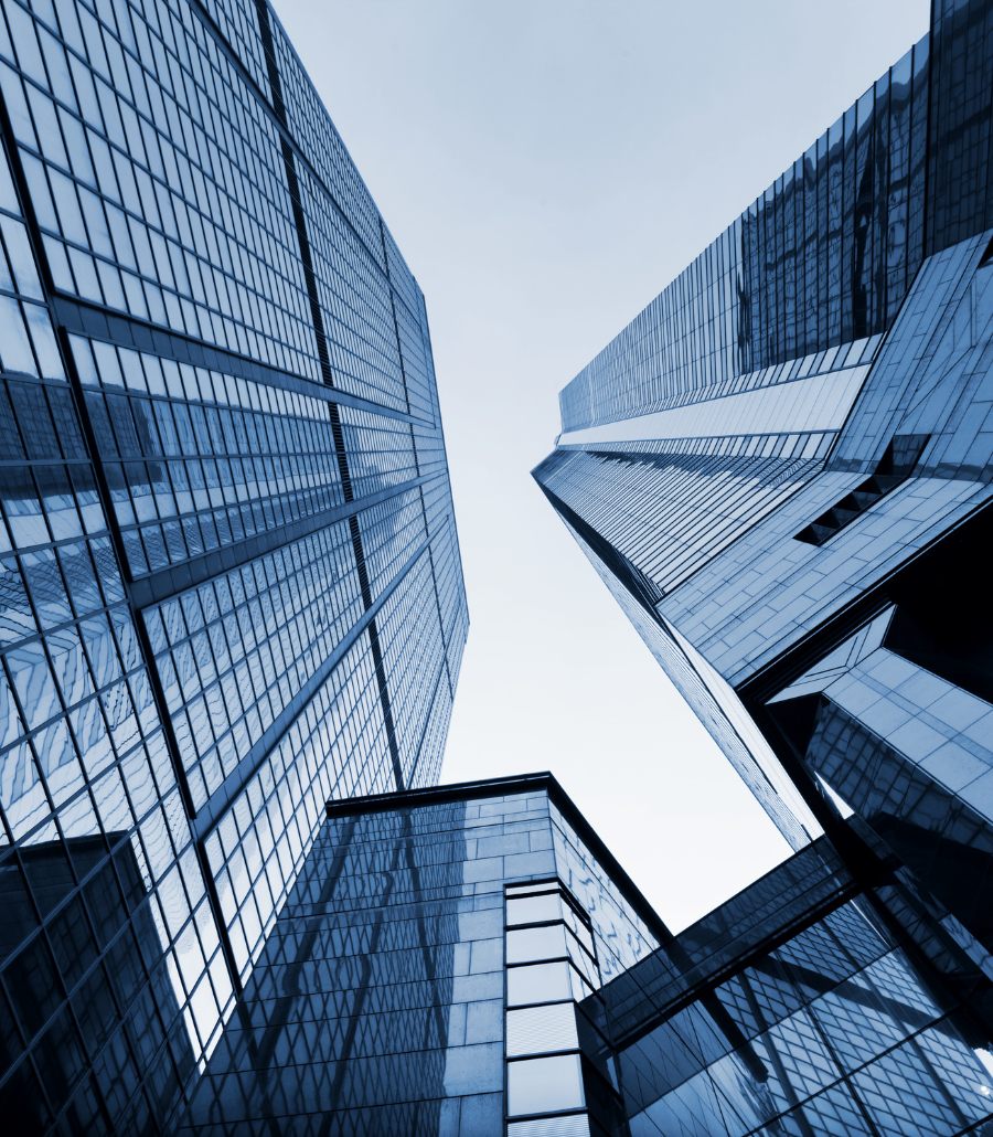 Glass office towers seen from below against a pale sky